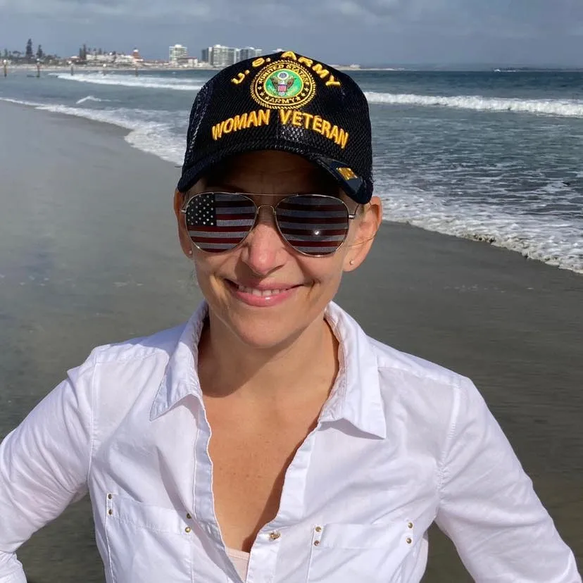 Mona at the beach in San Diego proudly wearing her US Army Woman Veteran ball cap and flag sunglasses