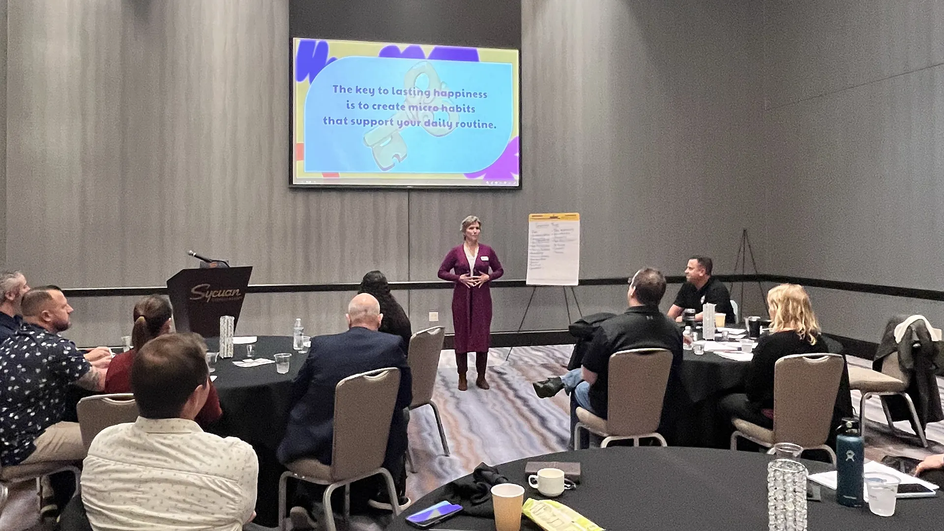 Mona speaking about micro habits to a group at a conference center breakout room.