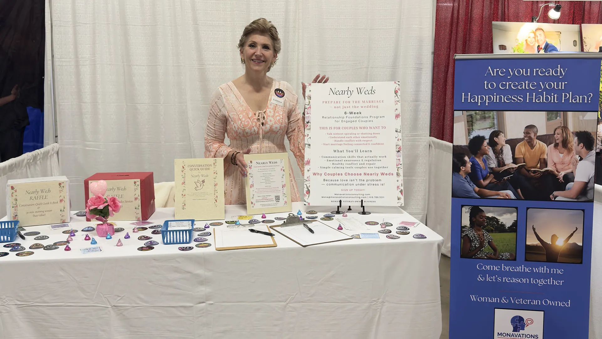 Mona at a trade show booth showing off her Nearly Weds package and a tall banner promoting her "Are you ready to create your Happiness Habit Plan?"