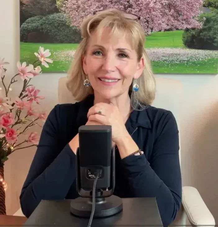 Screenshot of Mona from a video speaking at a microphone